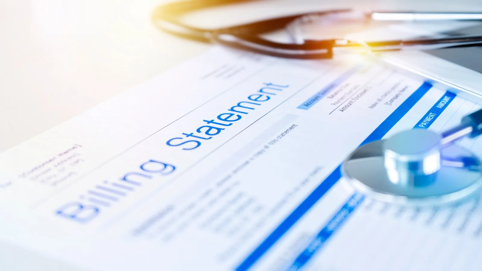 A printed billing statement on a desk beside reading glasses and a stethoscope
